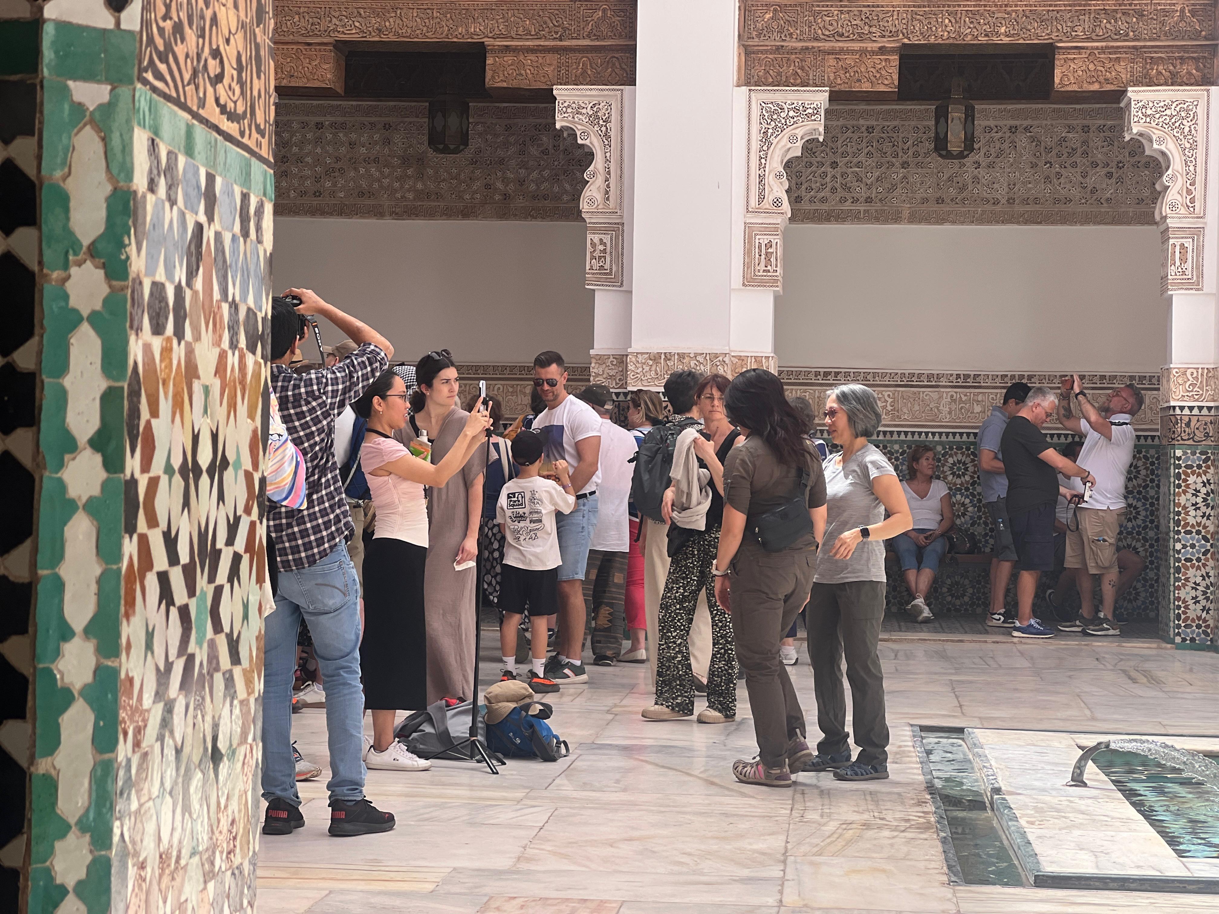 Tourists exploring traditional Moroccan palace with intricate tilework